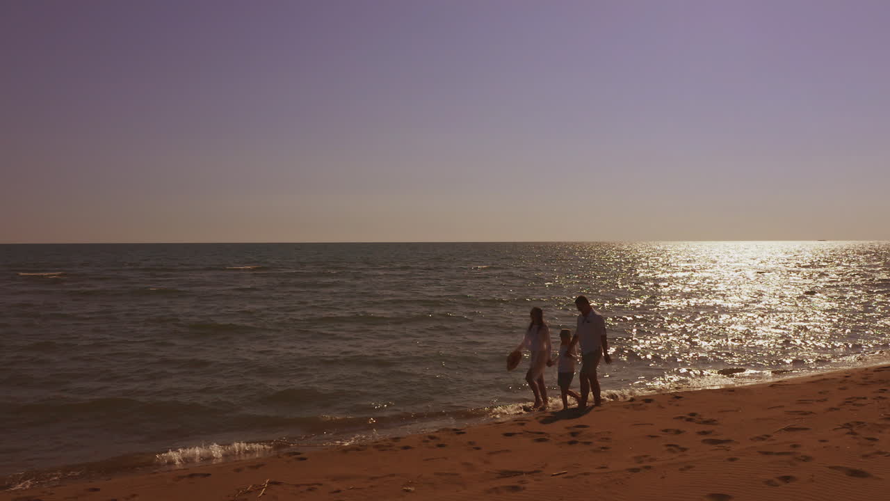 해가 지는 해변 산책을 즐기는 가족