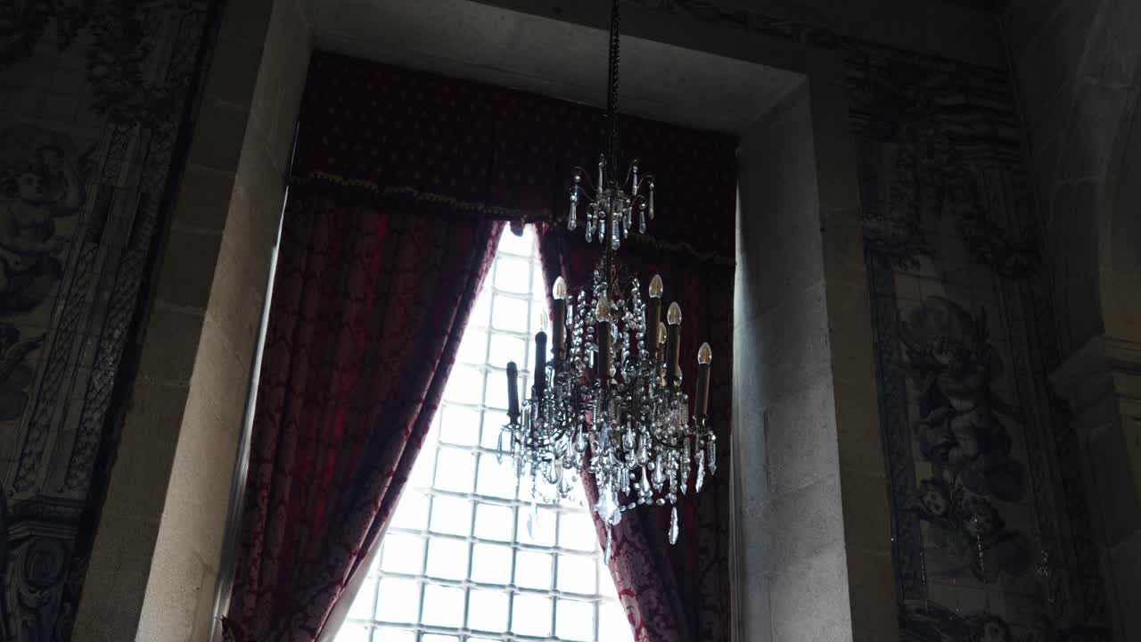 키가 큰 창가에 풍성한 드레이프와 함께 우아한 샹들리에가 걸려 있어요