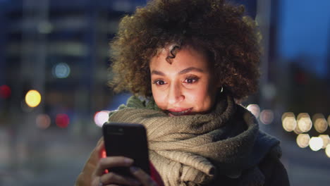 woman on city street at night ordering taxi using mobile phone app