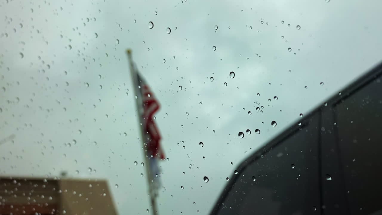 Water on a window, American flag flowing in the background