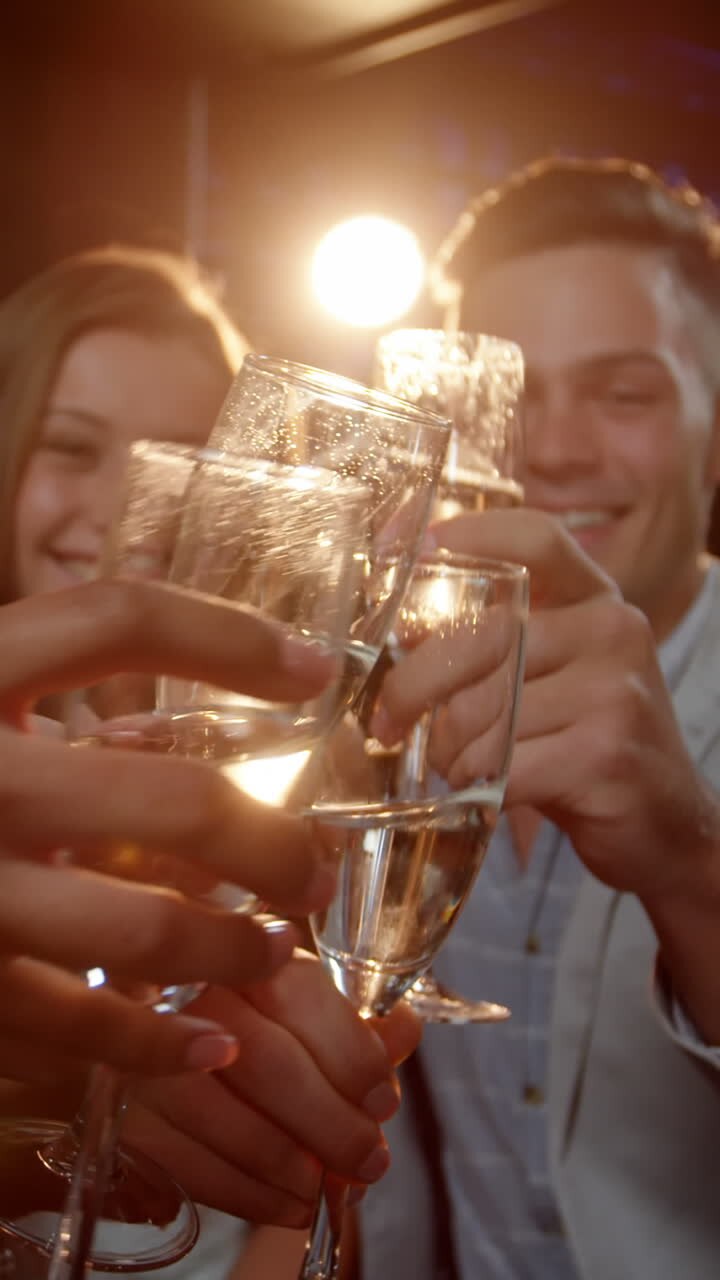 Group of smiling friends sitting on sofa and toasting a glasses of champagne