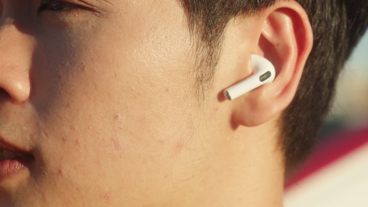 무선 헤드폰으로 음악을 듣는 동안 아시아 남성 초상화 눈이 닫힌 야외 이 많은 바람이 불는 여름 날