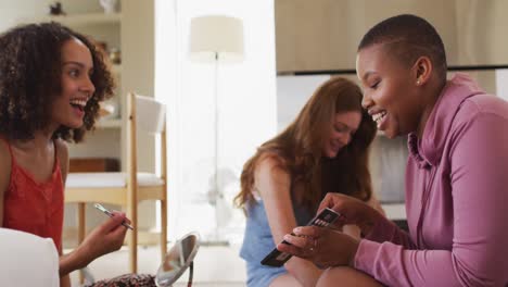 Diverse-group-of-happy-female-friends-trying-makeup-and-talking-at-home