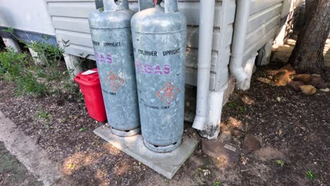 cilindros de gas al lado de una casa con un contenedor rojo