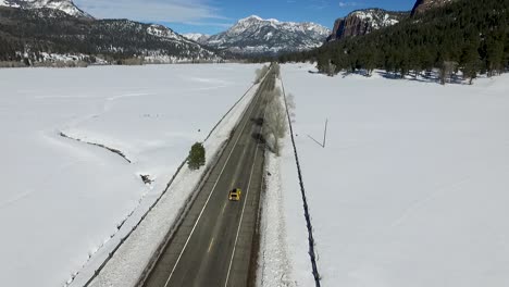 一架空中无人机在雪<unk>的冬季山上悬浮在高速公路旁边,