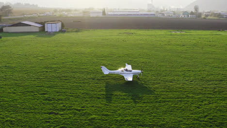 a single-engine white plane moving through the meadow in slovakia