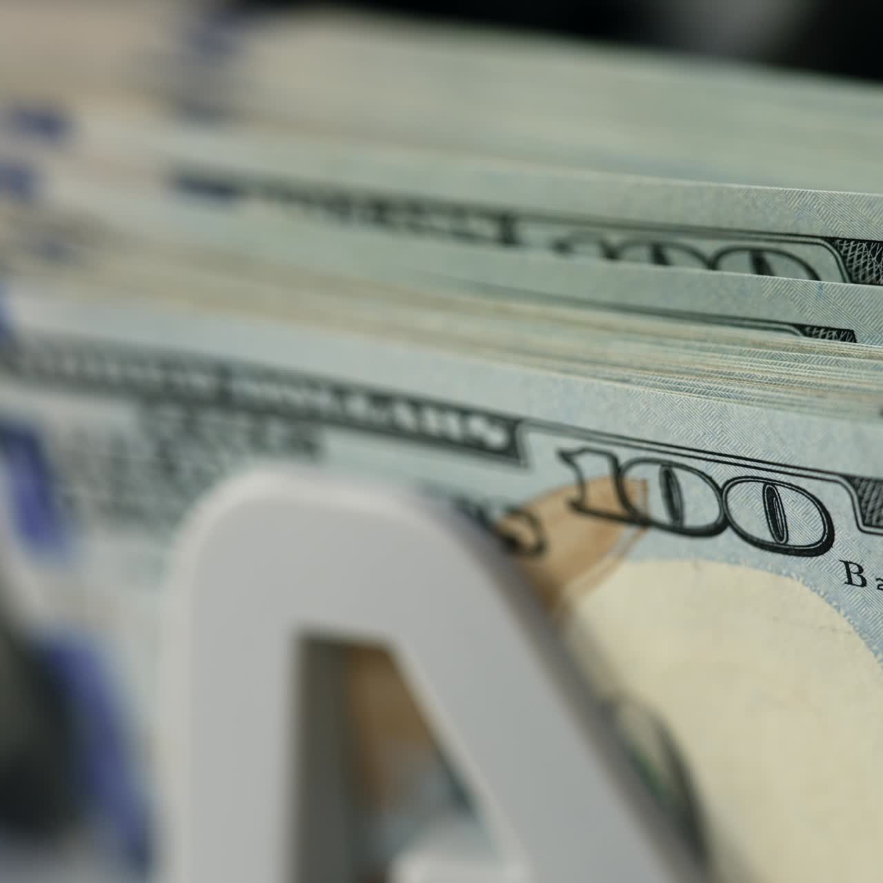 New hundred dollar bills quickly falling on the holder of machine. Close up. Financial equipment at work. Blurred backdrop