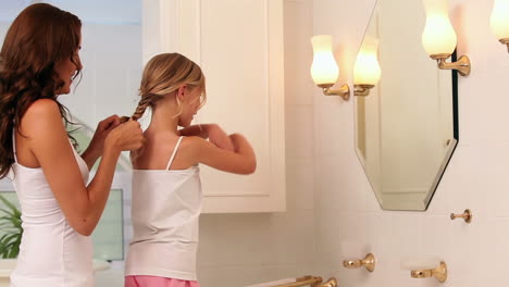 Mother-plaiting-her-little-girls-hair-in-the-morning