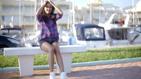 Young-Woman-Sitting-On-Bench-In-Harbor