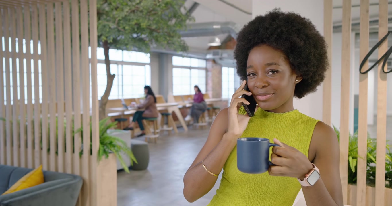 Chamada recebida mostrando uma mulher afro-americana atendendo ao telefone, bebendo de uma caneca azul e rindo em um lounge.