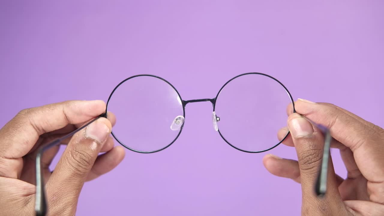 Hands holding round black glasses