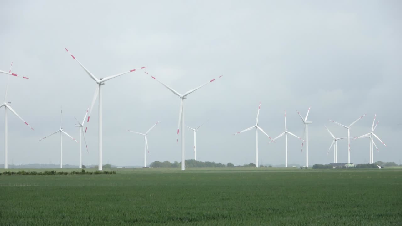 Panoramic view on alternative energy wind mills in a windpark with a cloudy sky.
