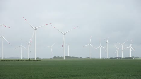 panoramic view on alternative energy wind mills in a windpark with a cloudy sky.