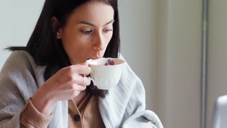 Woman-using-laptop-while-having-tea-4k