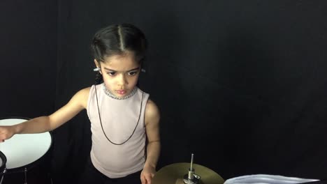 una niña de 5 años practicando la batería.