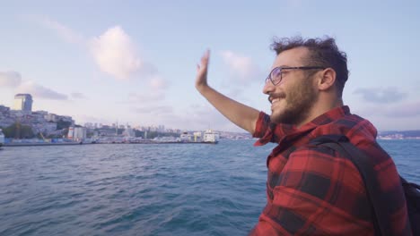un joven saludando desde el ferry, feliz.