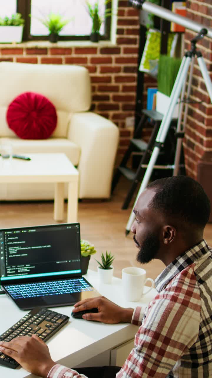 Vertical Video Young man seen programming software code on his laptop in a sleek home office