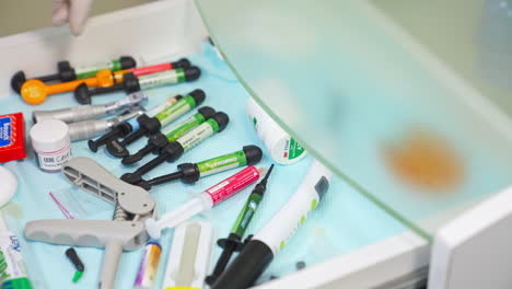 hand in latex glove opens a drawer with different dentistry tools and supplies. person chooses one of the nozzles for medical device. close up.