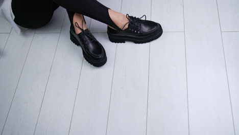 woman tying laces on black platform oxford shoes