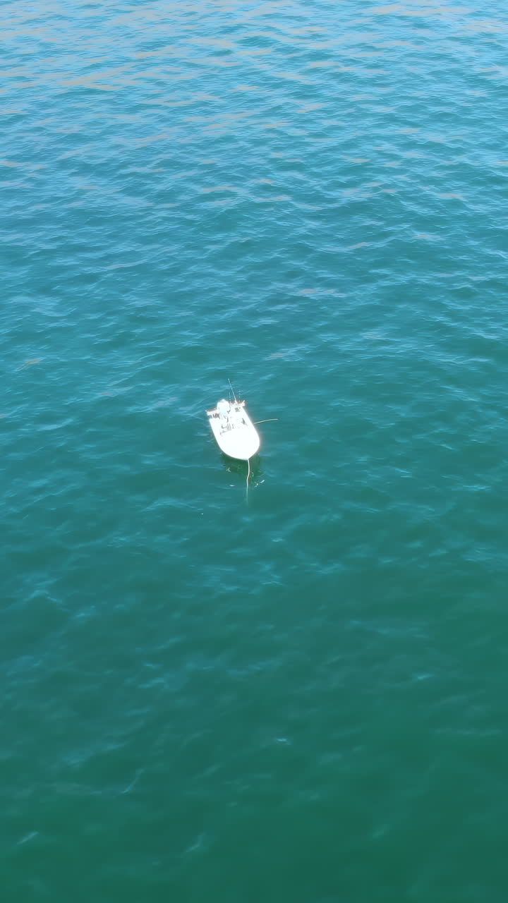 Small White Fishing Boat Floating in Calm Turquoise Ocean Water
