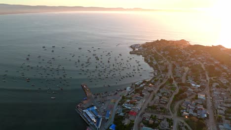 órbita aérea de la península de tongoy con varios barcos de pesca en su orilla con la puesta de sol y el mar de fondo, chile