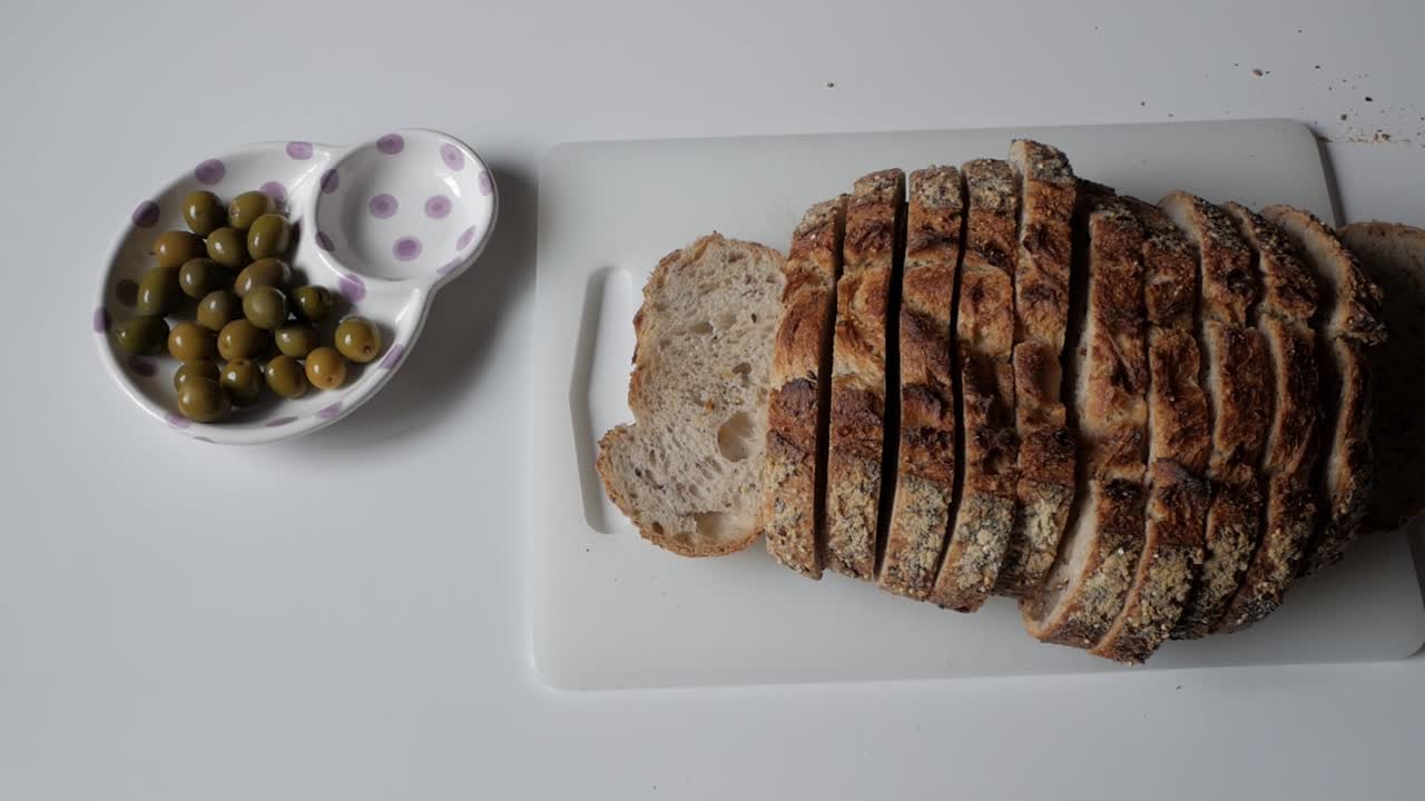 Sliced bread and olives on a white table create a cozy dining scene