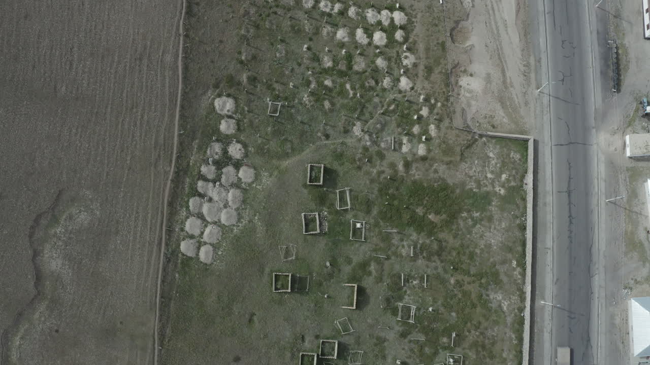 Abandoned rectangular structures and rocky formations near a road in Kyrgyzstan