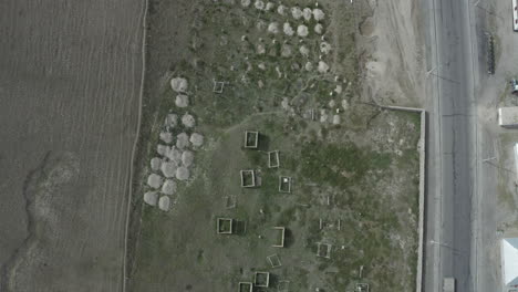 abandoned rectangular structures and rocky formations near a road in kyrgyzstan