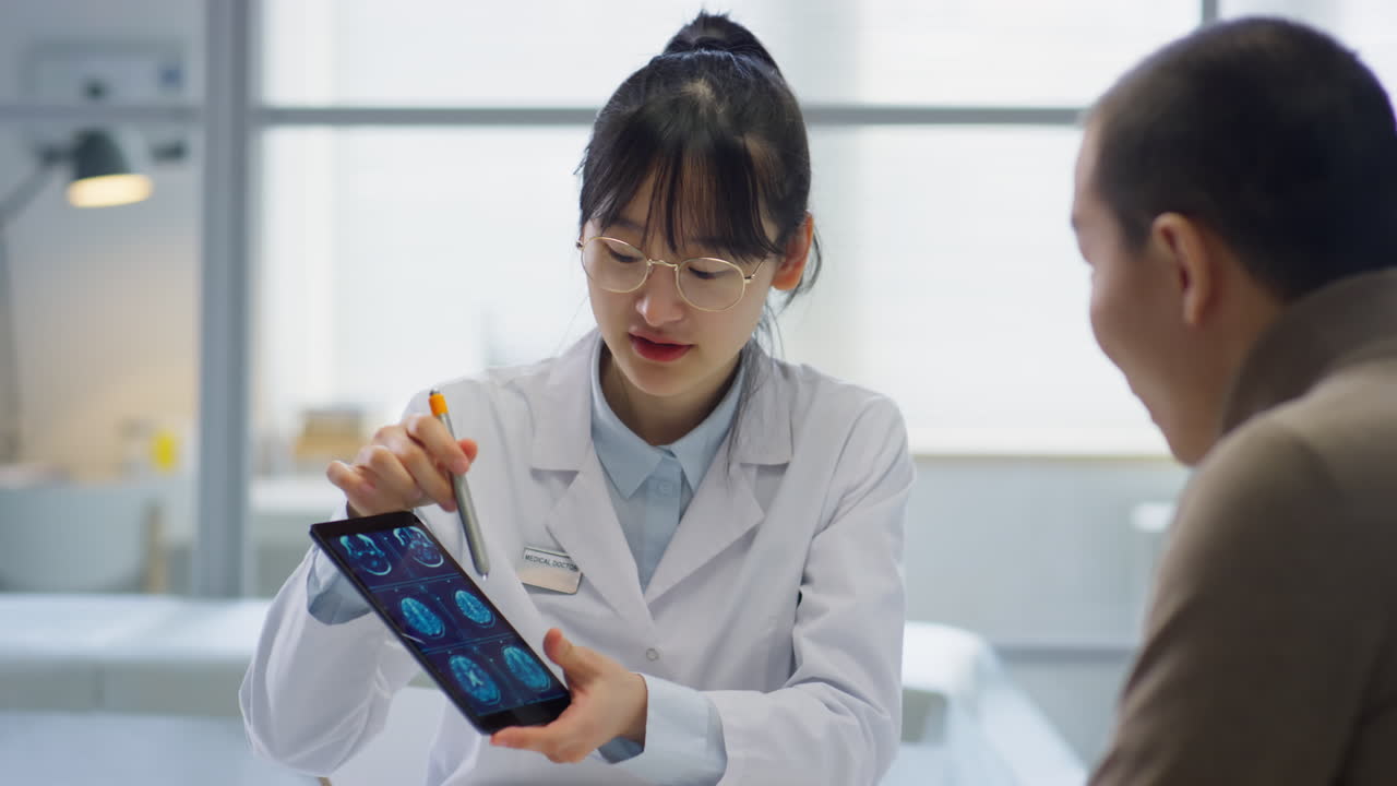 Asian Female Doctor Showing CT Scan on Tablet to Patient