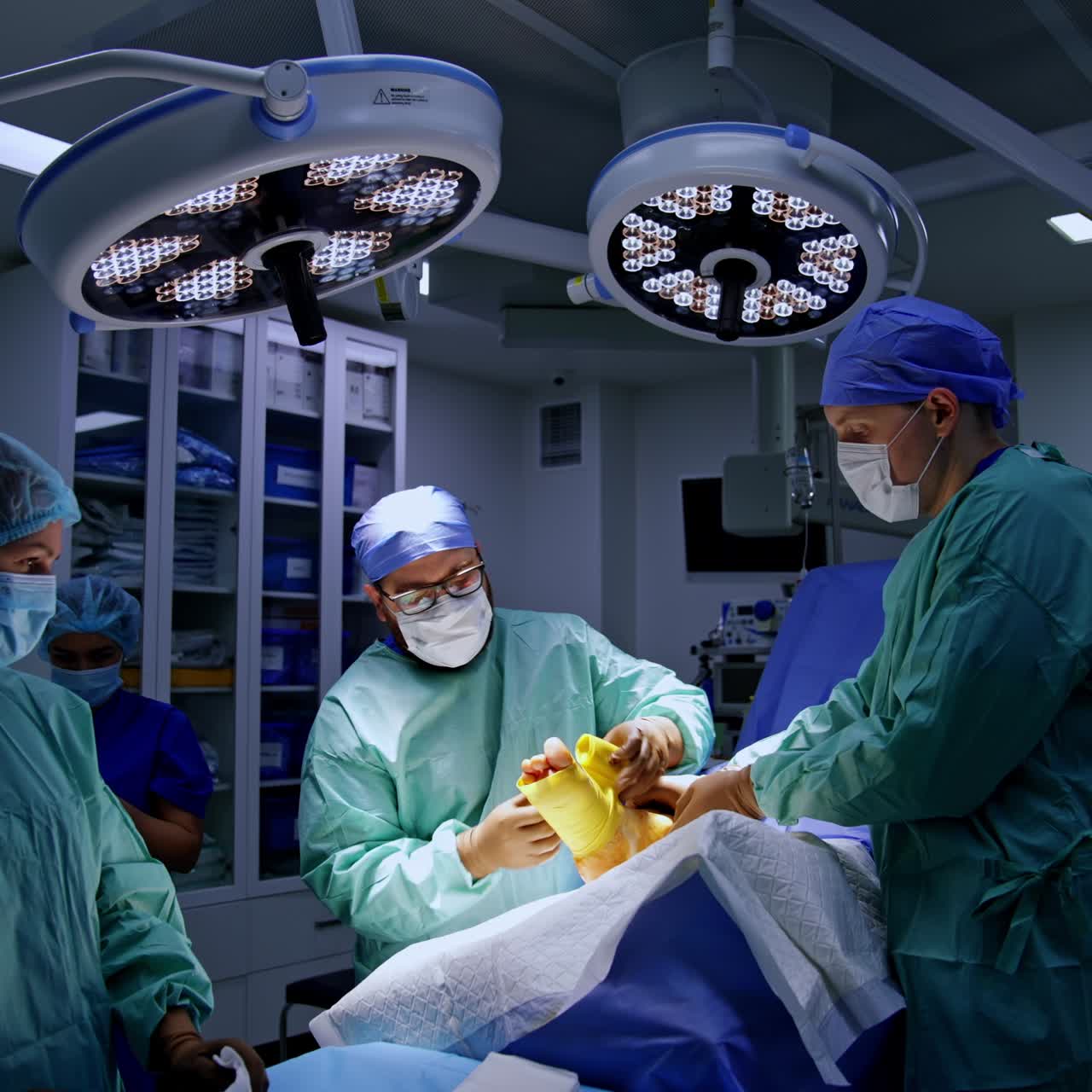Male doctor wearing eyeglasses puts the bandage on the patient's foot. Final stage of operation on foot