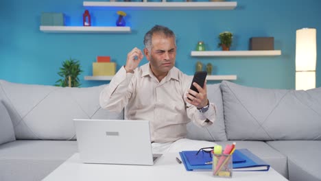 Home-office-worker-man-gets-frustrated-while-looking-at-phone.