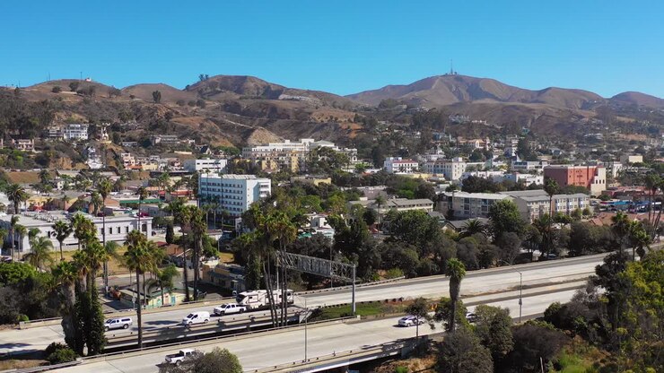 Una veduta aerea con drone della città costiera di Ventura, nel sud della California, con l'autostrada in primo piano e le montagne sullo sfondo 1