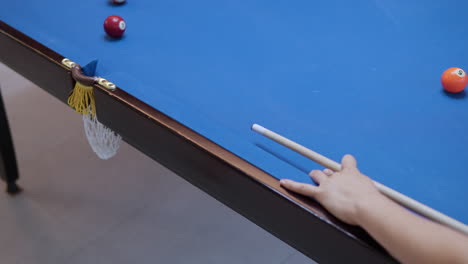 hand des mädchens in der nahaufnahme zielt und schlägt den weißen cue-ball, der sich auf die schiene stützt