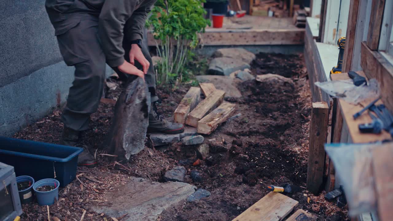 Man Carrying A Big Rock - Building A Greenhouse - Close Up