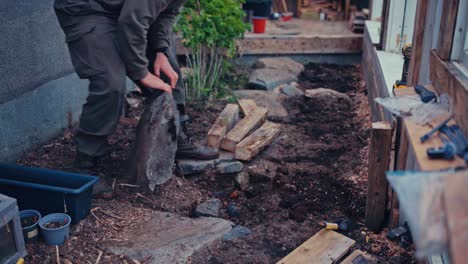 man carrying a big rock - building a greenhouse - close up