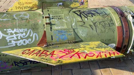 big missile rocket in mykhailivska square from the russia ukraine war in kyiv city center, burned and destroyed dangerous weapon of mass destruction, tanks in the background, 4k tilting up