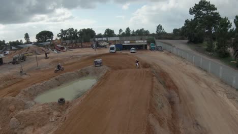 plataforma rodante aérea sobre pilotos de motocross haciendo banca y saltando en pista de tierra