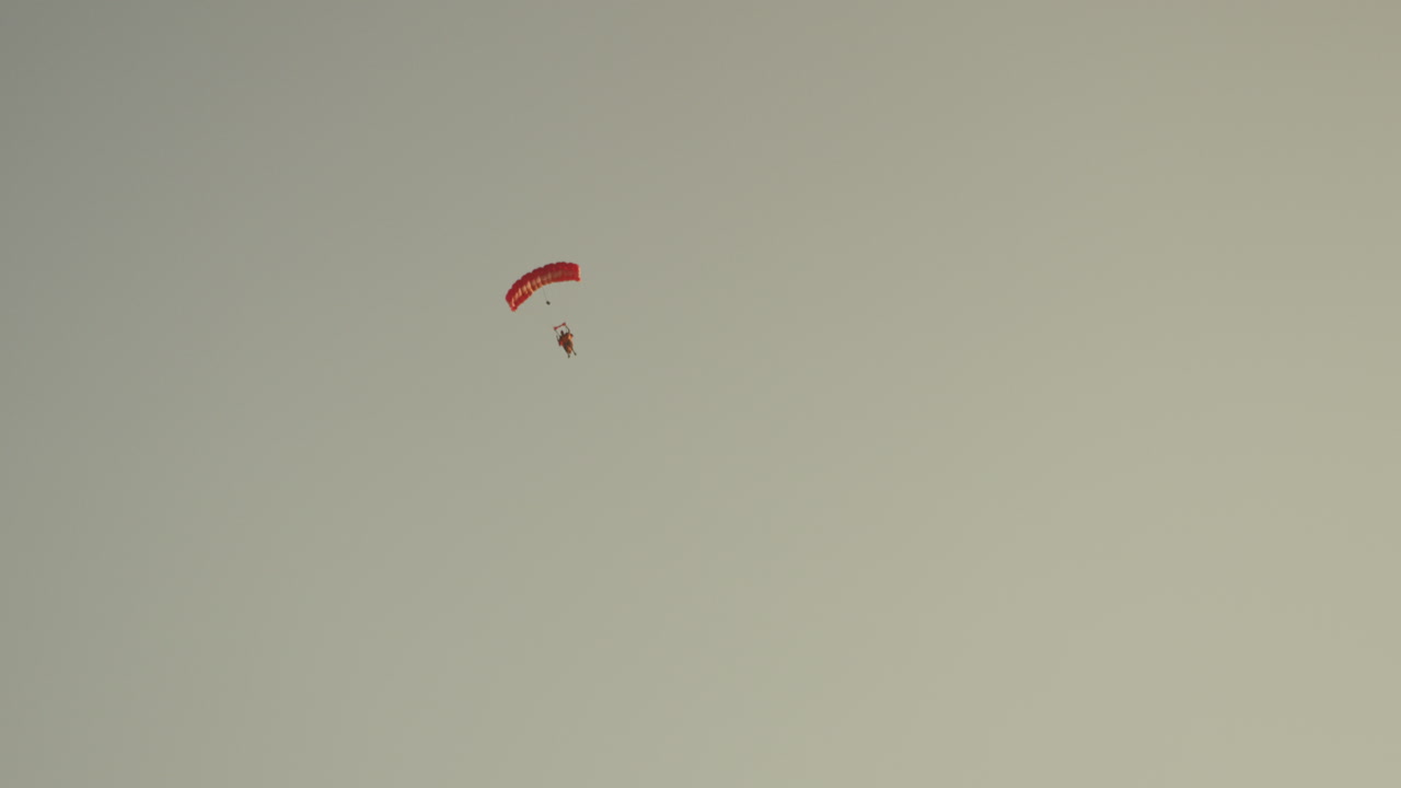una persona con un paracaídas rojo, cielo despejado