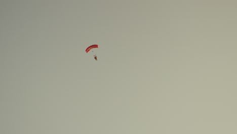 Eine-Person-Mit-Einem-Roten-Fallschirm,-Klarer-Himmel