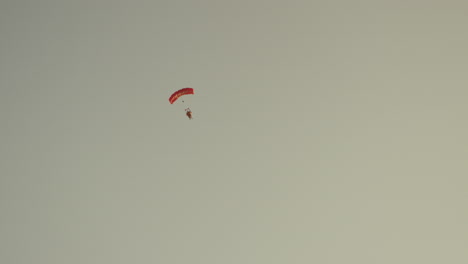 a person with a red parachute, clear sky