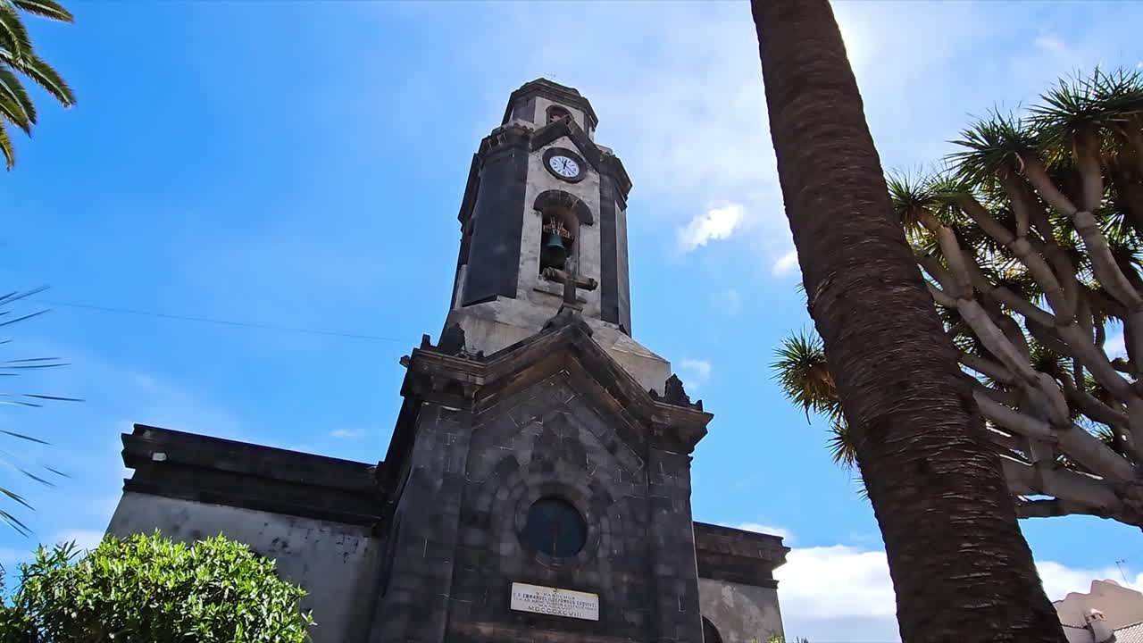 View of a church tower with a palm tree and clear sky in Puerto