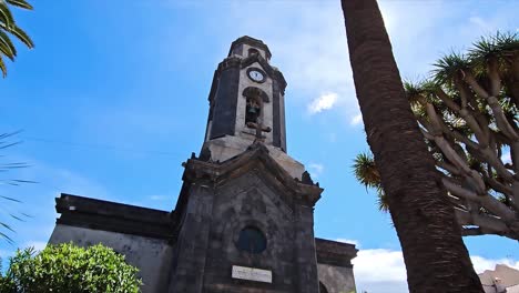 view of a church tower with a palm tree and clear sky in puerto