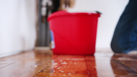 close up of man at home mopping up water from leaking pipe