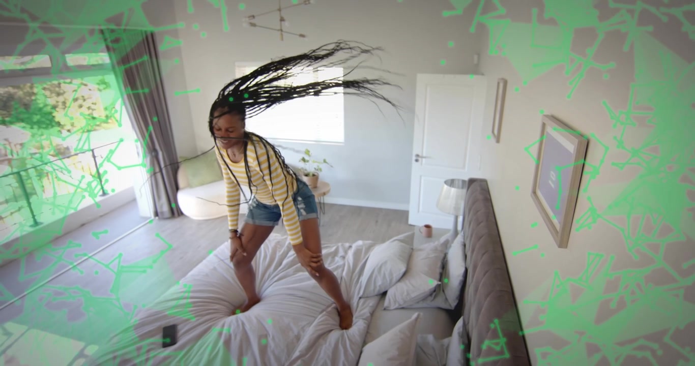 Woman bouncing on bed in sunlit room, shaking braids, causing smartphone sliding for entertainment