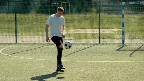 a young soccer man training freestyle tricks with the ball on a street football pitch on a sunny day 5