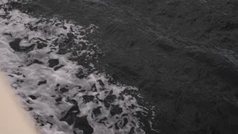 Side-perspective-of-ocean-over-edge-of-ferry-boat-to-reveal-stunning-deep-blue-sea-with-small-saves-and-ocean-spray-ripple