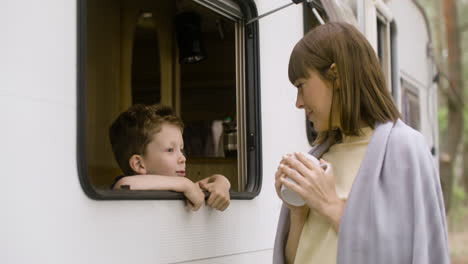 mother and son talking by the campervan in the forest