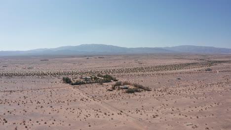 Absteigende-Und-Schwenkende-Luftaufnahme-Eines-Wüstenhauses-In-Der-Kalifornischen-Wüste