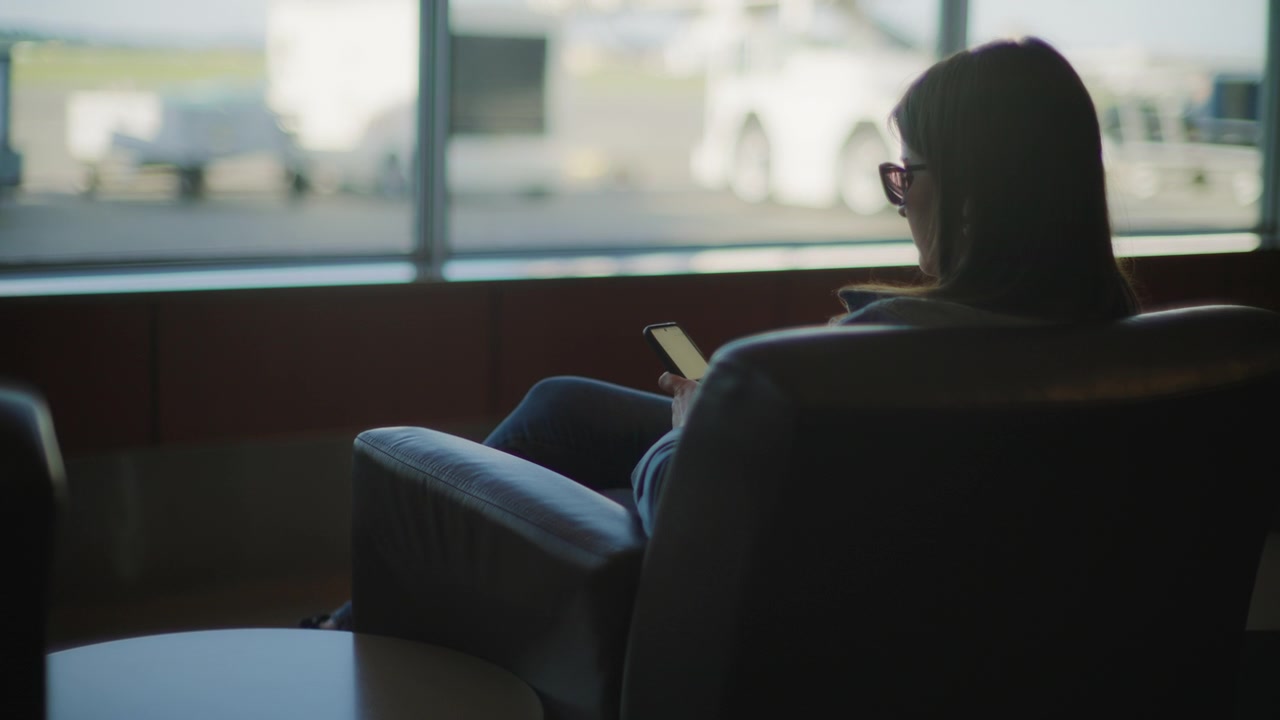 Donna che usa il telefono mentre aspetta di imbarcarsi su un aereo