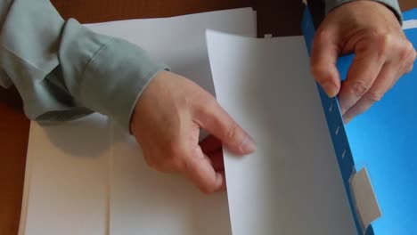 hands are placing papers in a file folder